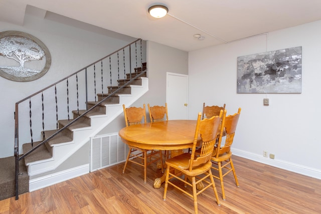 dining space with visible vents, baseboards, stairs, and wood finished floors