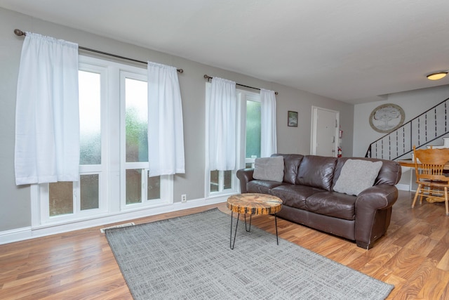living room with light wood-type flooring, stairs, and baseboards