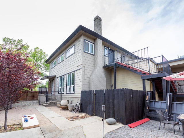 view of side of property with a fenced backyard, stairway, a patio area, and a chimney