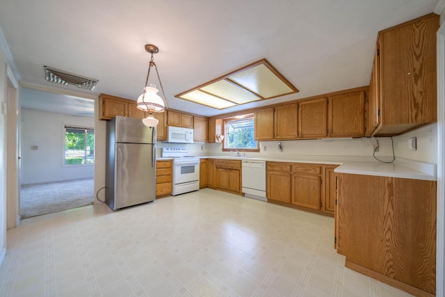 kitchen featuring sink, white appliances, plenty of natural light, and decorative light fixtures