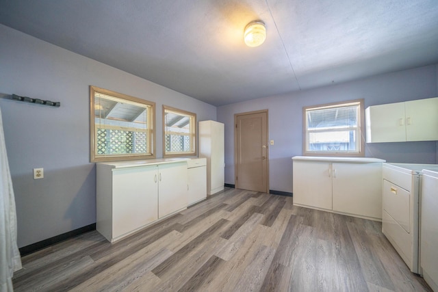 laundry area with cabinets, washer and clothes dryer, and light hardwood / wood-style floors