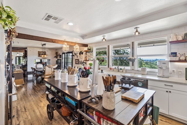 dining room with brick wall, a chandelier, and light hardwood / wood-style floors