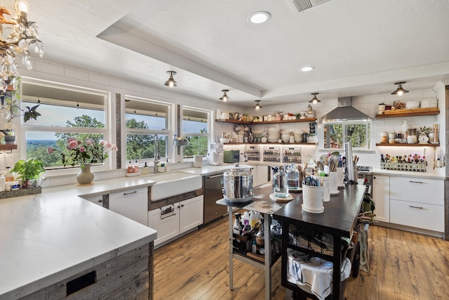 kitchen with white cabinetry, dishwasher, light hardwood / wood-style floors, and wall chimney range hood