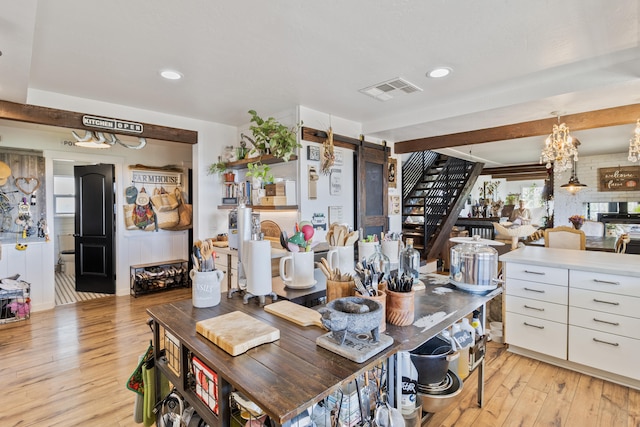 dining space featuring a notable chandelier, light hardwood / wood-style floors, and a barn door