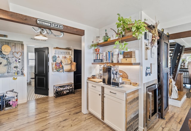 kitchen with tasteful backsplash, light hardwood / wood-style flooring, and white cabinets