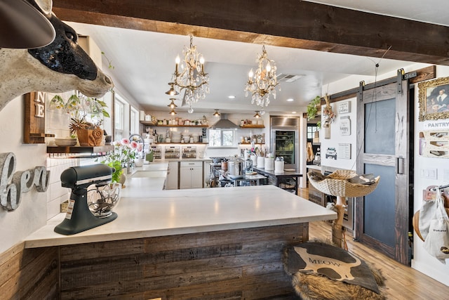 kitchen with hanging light fixtures, a barn door, plenty of natural light, and light hardwood / wood-style flooring