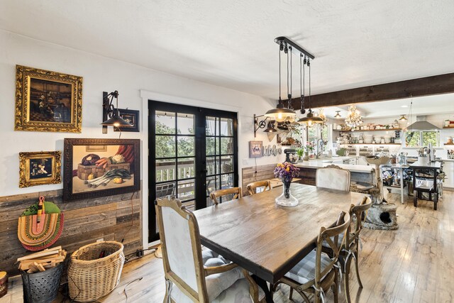 dining area featuring a wealth of natural light, a textured ceiling, light wood-type flooring, and french doors