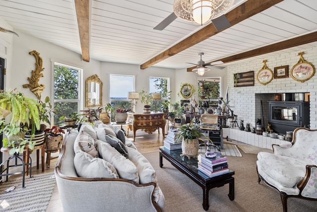 living room featuring ceiling fan, beam ceiling, a brick fireplace, and light wood-type flooring