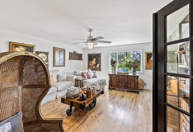 living room with ceiling fan, light hardwood / wood-style flooring, and a textured ceiling