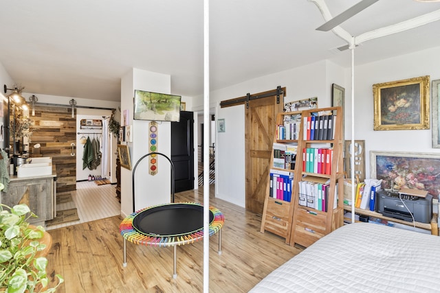 bedroom with a barn door and light hardwood / wood-style floors