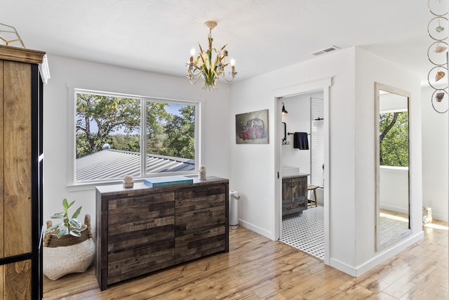 hallway with an inviting chandelier, a healthy amount of sunlight, and light hardwood / wood-style flooring