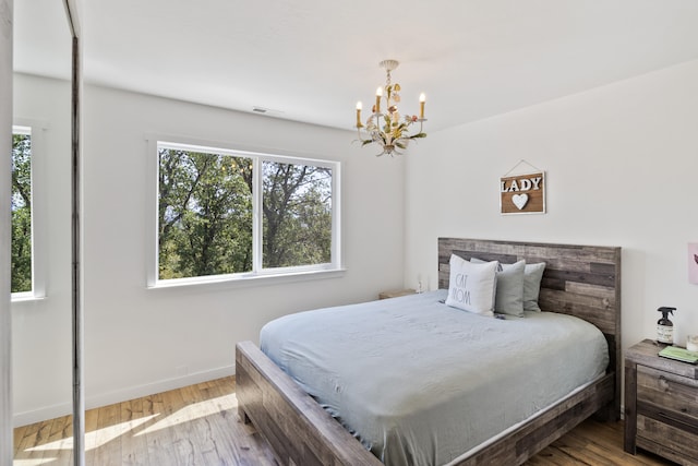 bedroom with a notable chandelier and light wood-type flooring