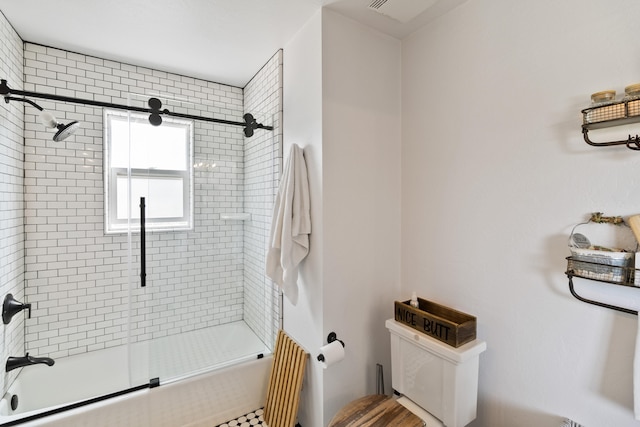 bathroom with bath / shower combo with glass door and toilet