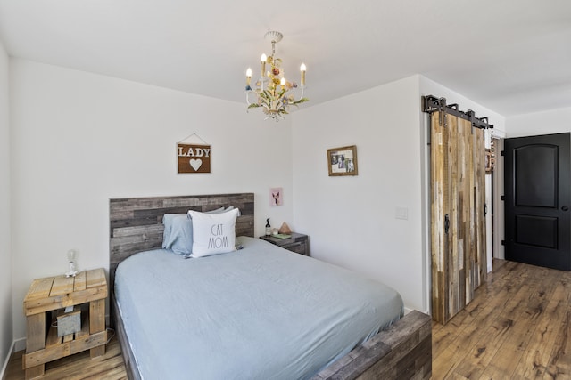 bedroom featuring hardwood / wood-style flooring, a barn door, and a notable chandelier