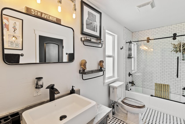 full bathroom with enclosed tub / shower combo, vanity, and toilet