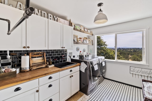 clothes washing area with cabinets, washing machine and dryer, and sink