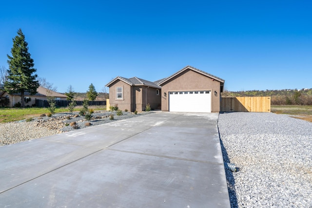 ranch-style house with driveway, fence, an attached garage, and stucco siding