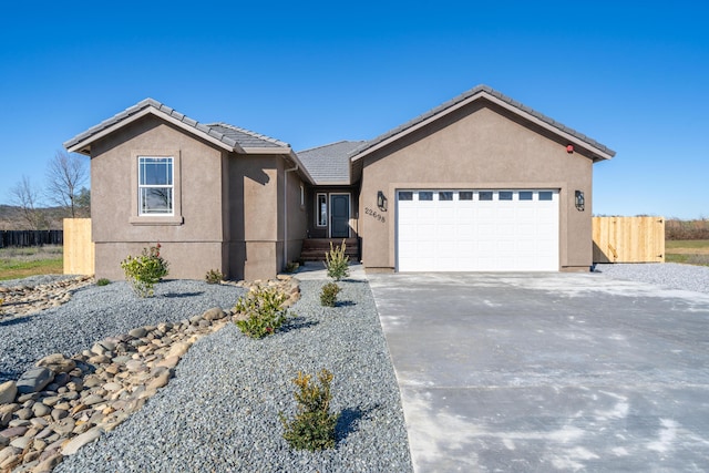 ranch-style house with a garage, fence, driveway, and stucco siding