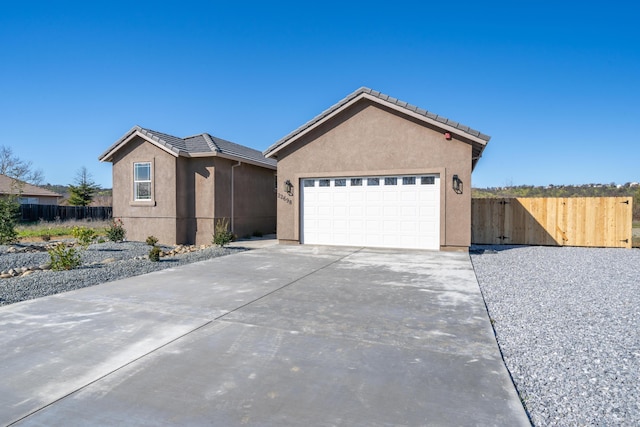 single story home featuring a garage, a tile roof, concrete driveway, and stucco siding