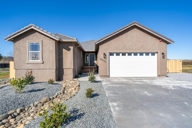 ranch-style house featuring concrete driveway, an attached garage, a tile roof, and stucco siding