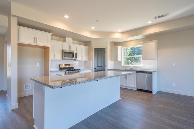 kitchen featuring visible vents, appliances with stainless steel finishes, a kitchen island, and white cabinetry