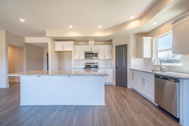 kitchen featuring stainless steel appliances, white cabinetry, a kitchen island, and a sink