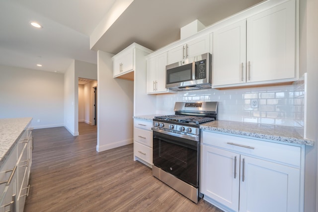 kitchen featuring appliances with stainless steel finishes, wood finished floors, white cabinetry, and tasteful backsplash