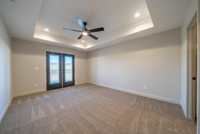 spare room featuring a raised ceiling, light colored carpet, baseboards, and french doors