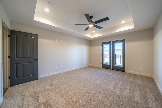 unfurnished room with baseboards, french doors, a raised ceiling, and light colored carpet