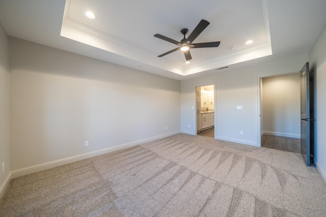 unfurnished bedroom with light colored carpet, baseboards, a raised ceiling, and recessed lighting