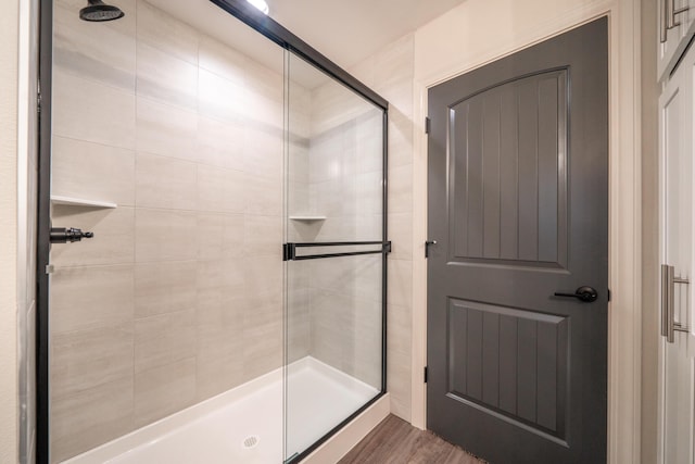 bathroom featuring wood finished floors and a shower stall