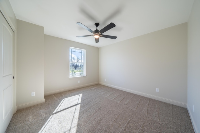 unfurnished room featuring a ceiling fan, light colored carpet, and baseboards