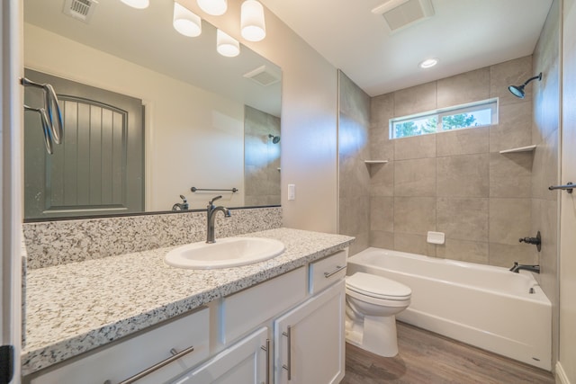 bathroom featuring visible vents, toilet, shower / tub combination, wood finished floors, and vanity