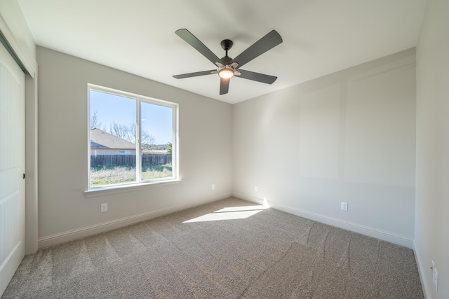 carpeted empty room with ceiling fan and baseboards