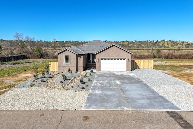 view of front of house featuring driveway, an attached garage, fence, and stucco siding