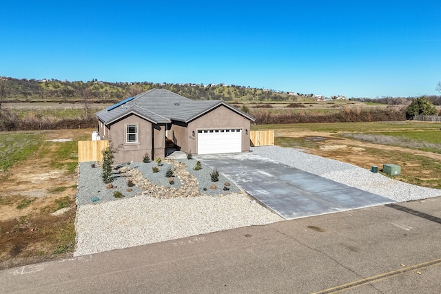 view of front of property featuring a garage, driveway, fence, and stucco siding