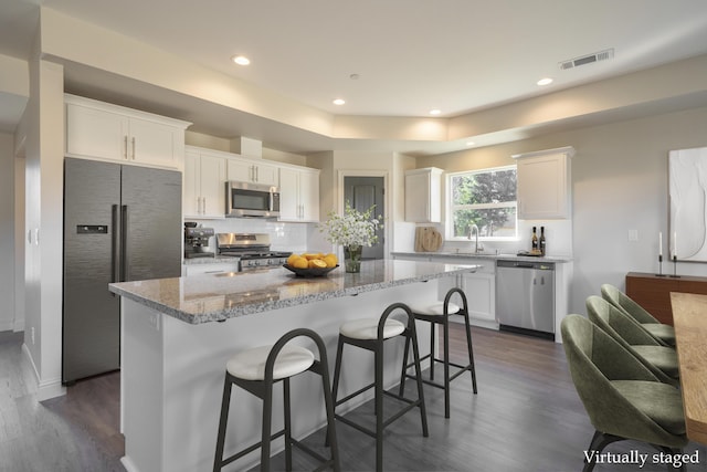 kitchen with visible vents, white cabinets, appliances with stainless steel finishes, a center island, and a sink