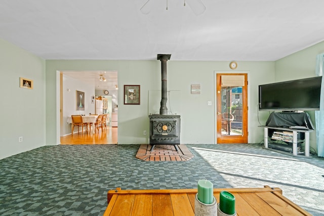 living room with ceiling fan and a wood stove