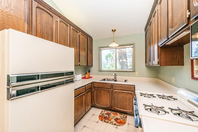 kitchen with white refrigerator, range, sink, light tile floors, and pendant lighting