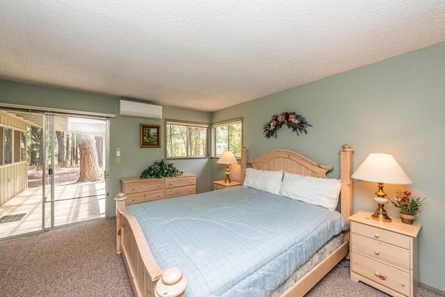 carpeted bedroom with access to outside, a wall mounted AC, and a textured ceiling