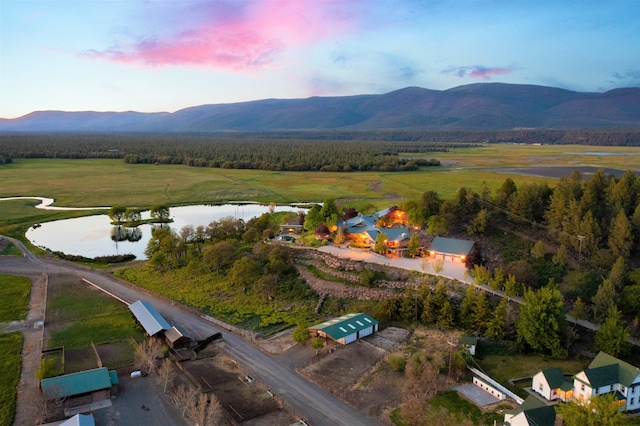 aerial view at dusk with a water and mountain view and a rural view