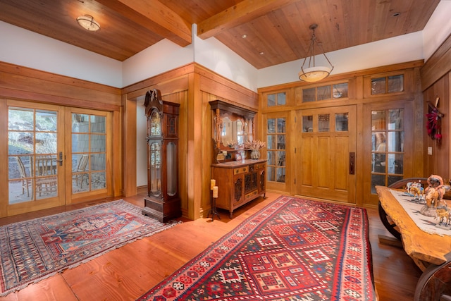 foyer entrance featuring french doors, wooden walls, hardwood / wood-style floors, and beam ceiling