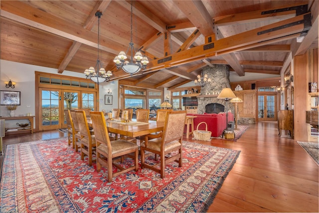 27744 Lee Rd, Mcarthur, CA 96056 - dining room with lofted ceiling with beams, a chandelier, a stone fireplace, hardwood / wood-style floors, and wooden ceiling