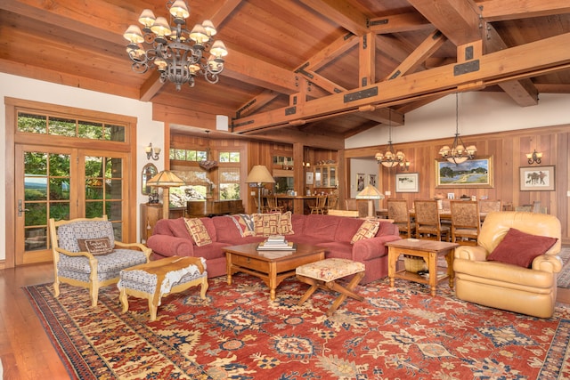 living room featuring an inviting chandelier, a healthy amount of sunlight, hardwood / wood-style flooring, and wooden walls