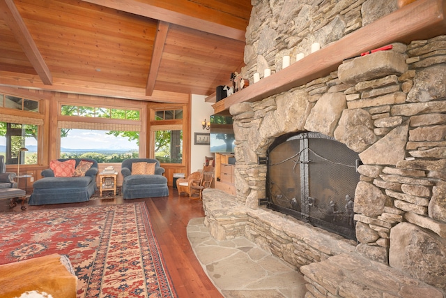 living room with hardwood / wood-style flooring, a stone fireplace, lofted ceiling with beams, and wooden ceiling