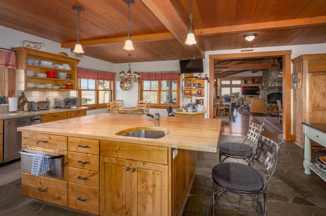 kitchen featuring a stone fireplace, dishwasher, butcher block countertops, and a wealth of natural light