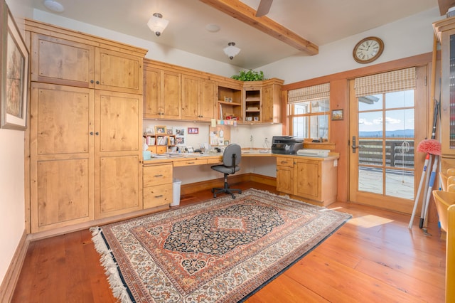 home office featuring light hardwood / wood-style flooring, beam ceiling, and built in desk