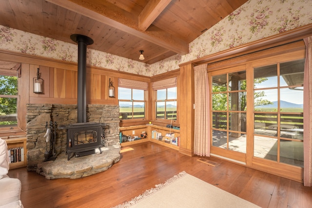 living room featuring vaulted ceiling with beams, wooden ceiling, hardwood / wood-style flooring, and a wood stove