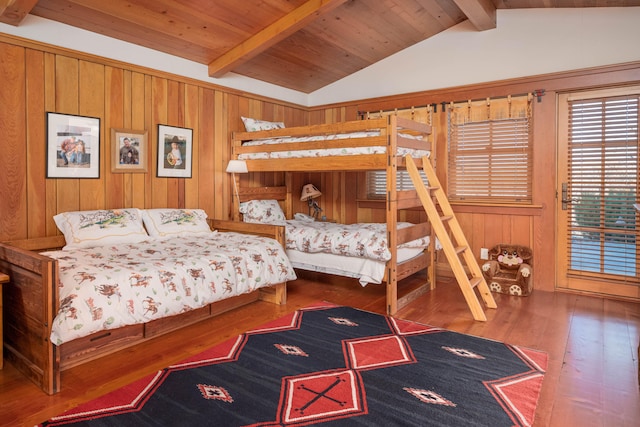 bedroom with wooden walls, hardwood / wood-style floors, wooden ceiling, and vaulted ceiling with beams