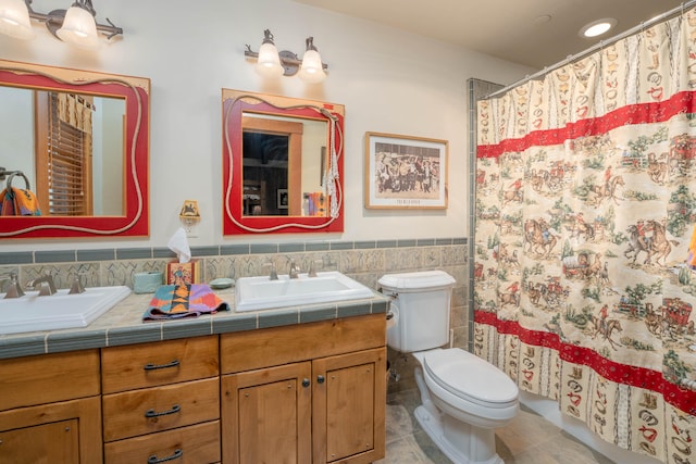 bathroom with double sink vanity, toilet, tile walls, tile patterned floors, and decorative backsplash